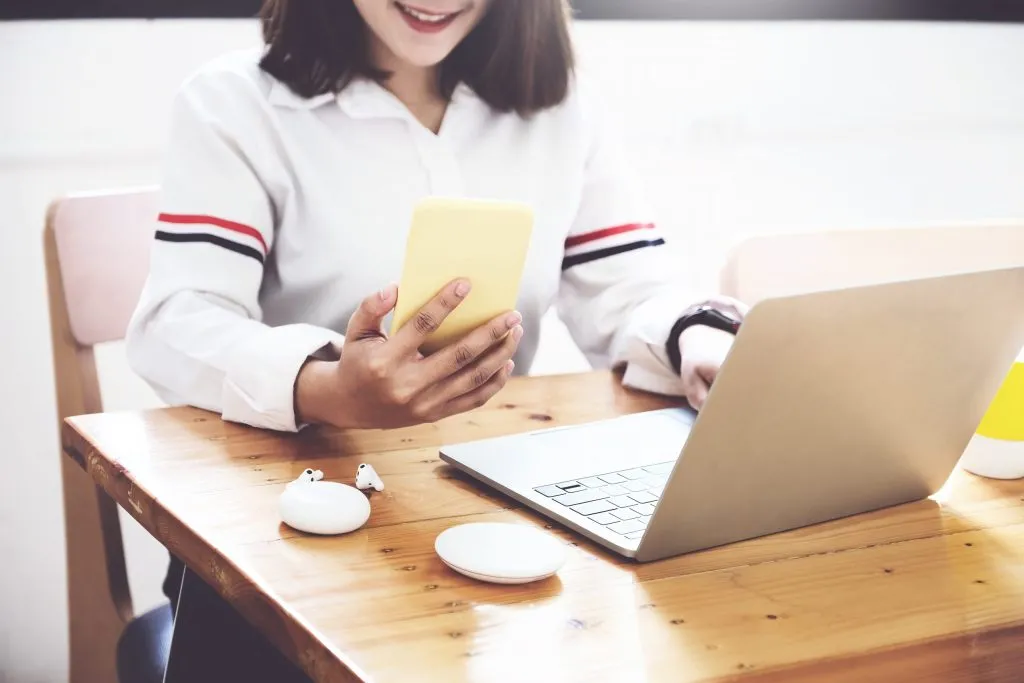 midsection-woman-using-smart-phone-while-sitting-table